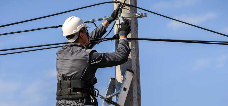 Person on a ladder working with communications wires.