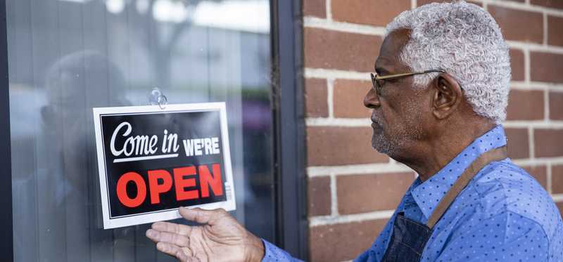 Person turning over the open sign on a storefront to start the day.