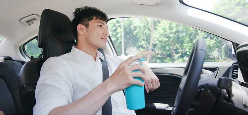Person holding a cup while riding in an autonomous self-driving car.