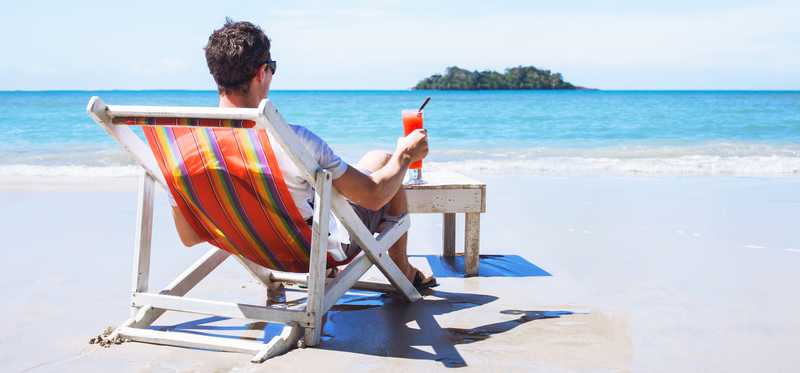 Man sitting on a beach chair facing the ocean.