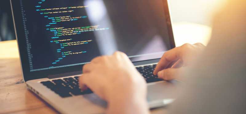 Man typing in code on laptop.