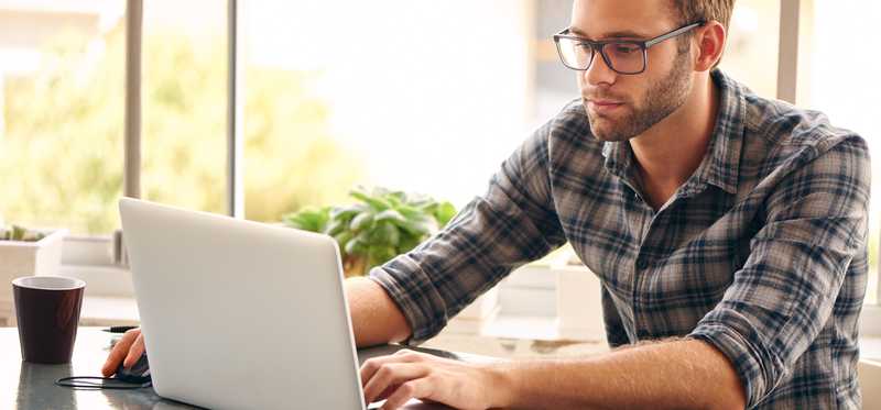A man typing on a laptop at a table