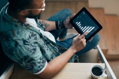 Person uses tablet to view graph while enjoying coffee.