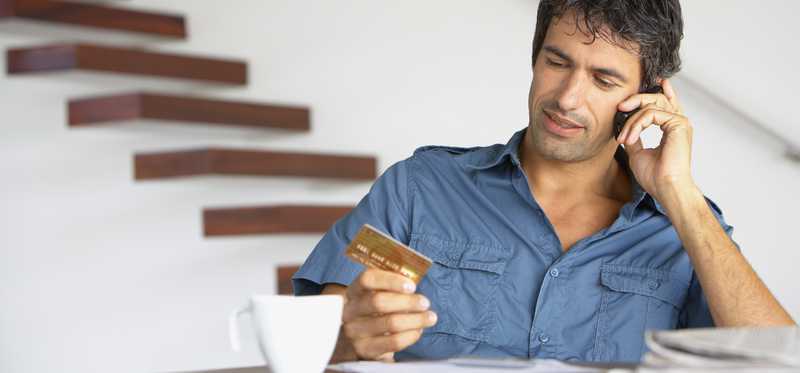 Person holding credit card and talking on phone.