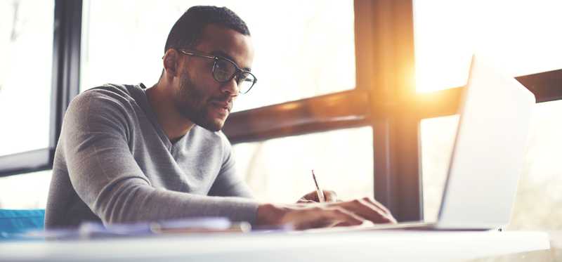 Person with serious expression working at laptop.