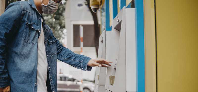 Man wearing face mask completing transaction at ATM