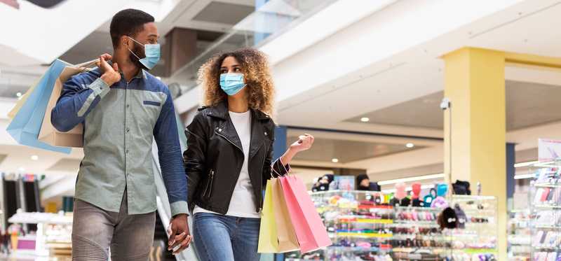 Two people holding hands and shopping bags while shopping.
