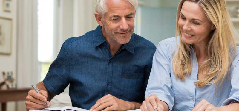 Two people discussing finances with pens and paper.
