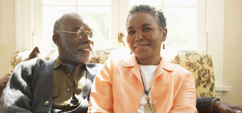 Two people sitting on couch and holding hands.