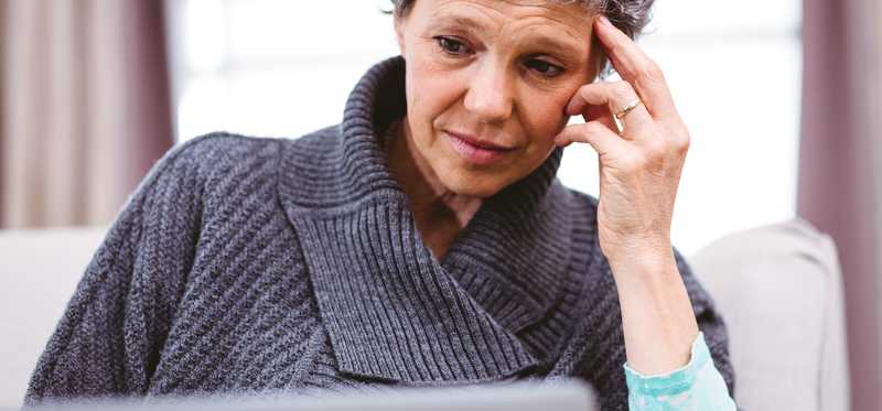 Person looking at a laptop computer and thinking.
