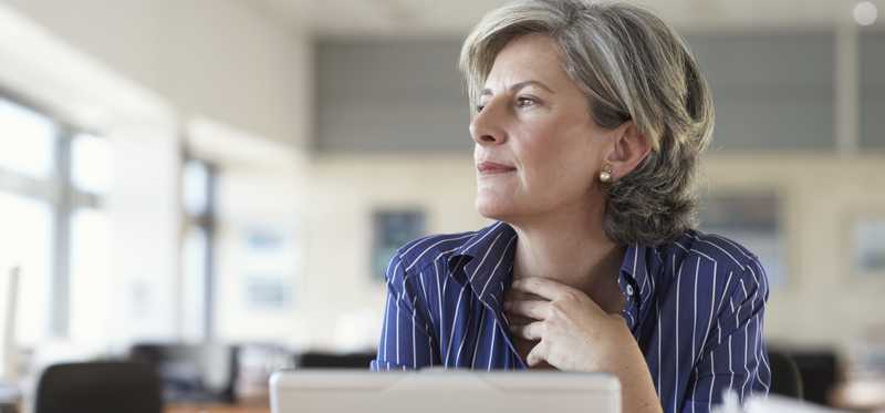Person on laptop is thinking and looking out window.