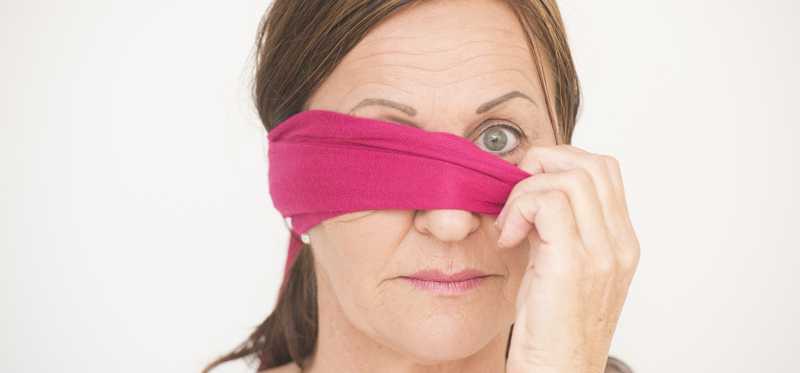Mature woman removing blindfold.