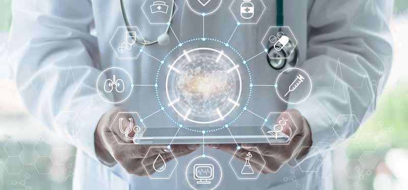 Person with stethoscope holding iPad with stylized medical-related icons in foreground.