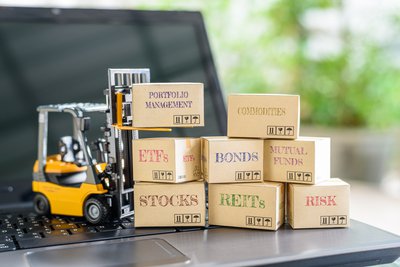 Miniature forklift on open laptop is pushing building blocks marked with different types of investments.