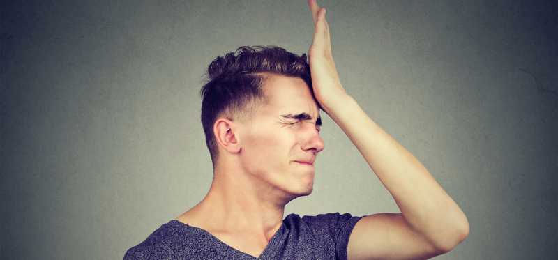 Young man with palm to head as if frustrated with himself.
