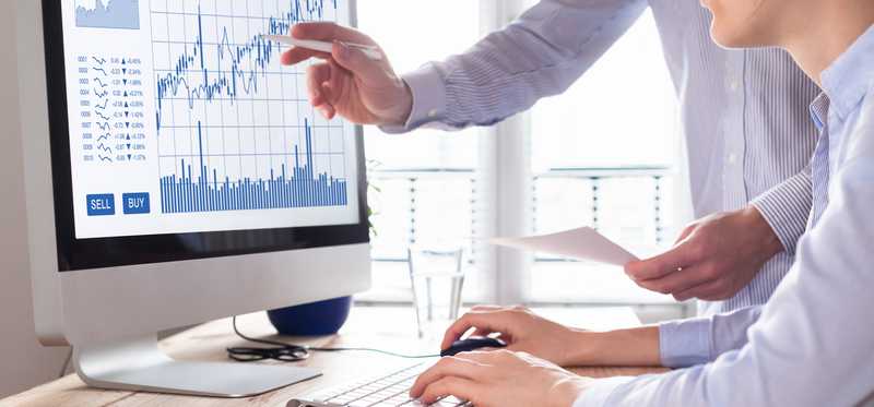Two workers monitoring stock on computer screen