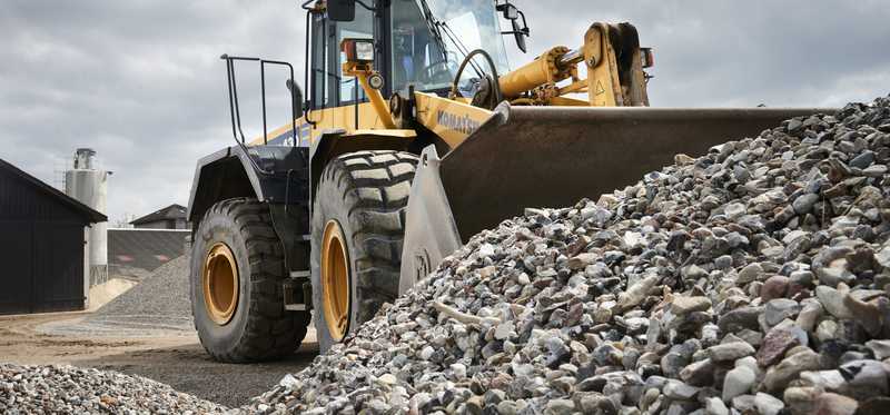 Gravel being moved by a front-end loader.