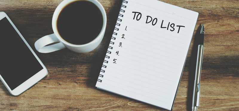 A notebook with a to-do list, cell phone, cup of coffee, and a pen.