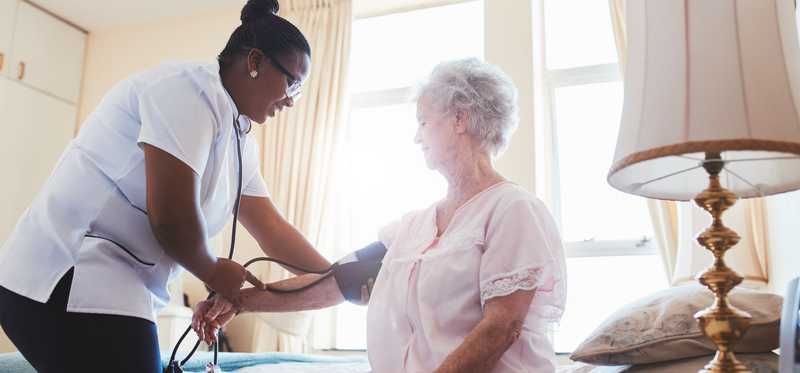 nurse checking elderly patients blood pressure