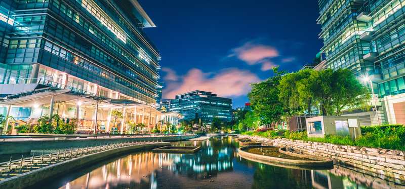 Modern office buildings situated on both sides of a lovely waterway winding itself through Hong Kong.