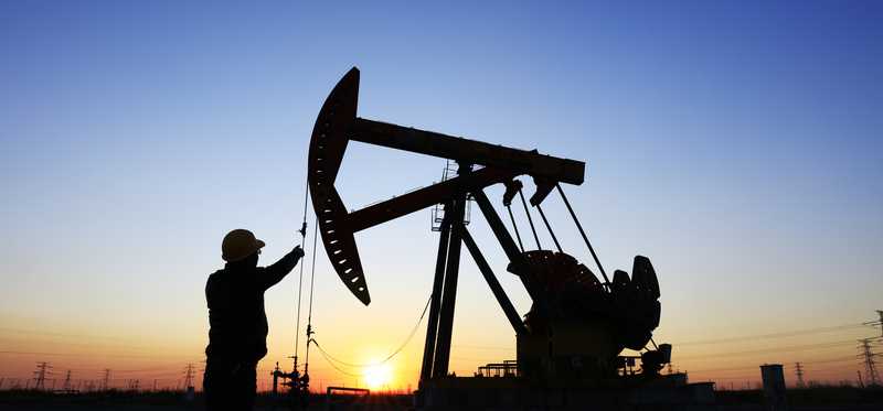 Worker and oil pumpjack at sunset.