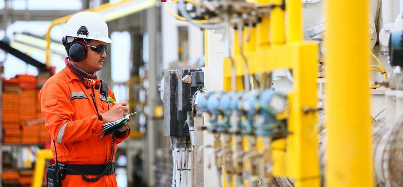 An oil and gas worker in an orange jumpsuit and glasses.