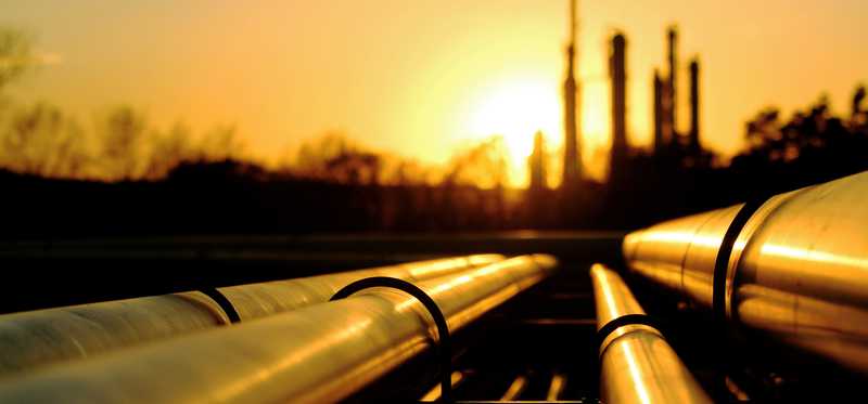 Oil pipes with a refinery in the distance.