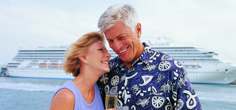 Older couple in front of a cruise ship.
