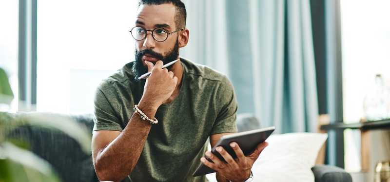 A man holding a tablet and stylus thinking.