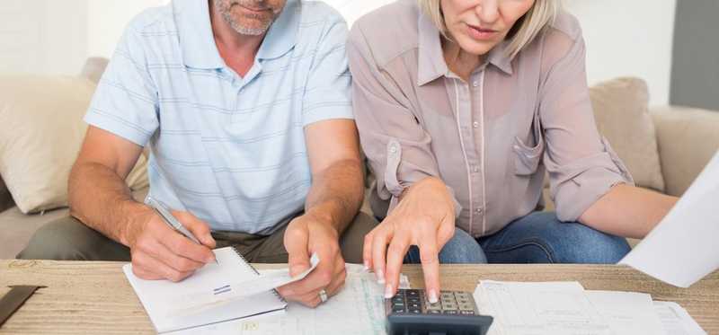 Old couple looking at financial documents and using a calculator