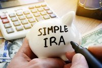 SIMPLE IRA written with a thick black marker on a white piggy bank.
