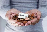 Person holds out hands holding pennies and a piece of paper that reads "retirement."