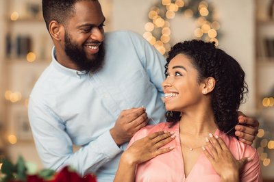 Luxury Present. Smiling Black Young Lady Receiving Golden Pendant Necklace With Diamond For Holiday. Happy Lovely Couple Celebrating St Valentine's Day, Anniversary, Engagement Or Birthday