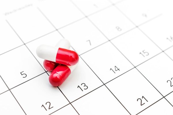 Red and while pills on top of a calendar.