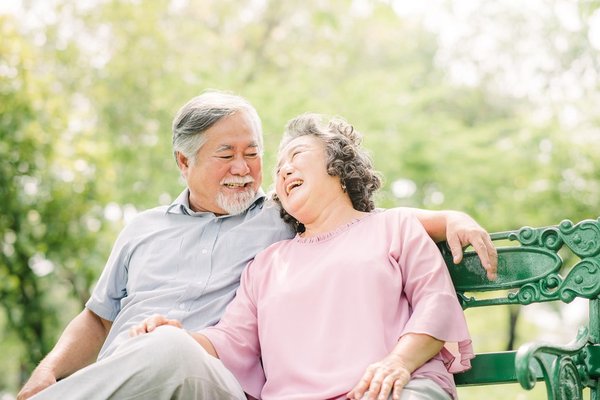 Smiling older couple sitting on a bench.