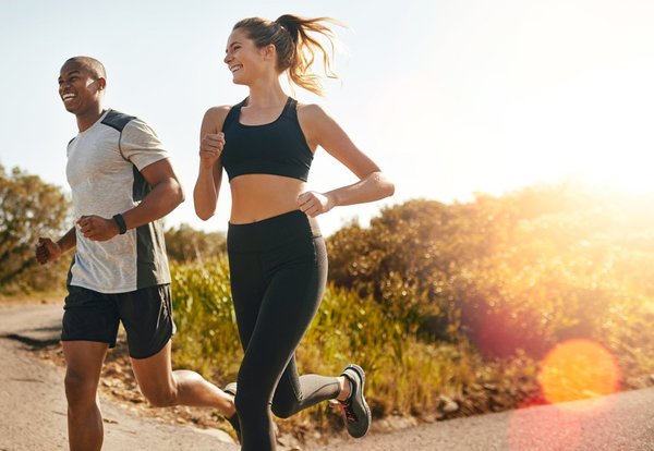 A man and woman smiling while jogging together.