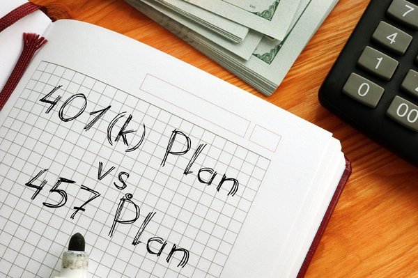 A stack of bills, a calculator, and a notebook with the words "401(k) Plan vs. 457 Plan" written in it.