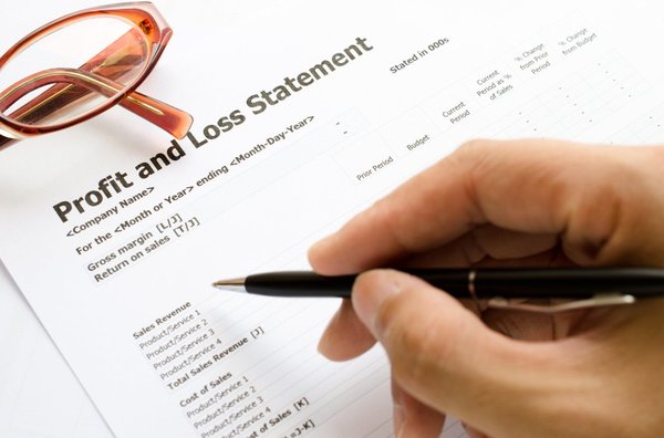 A person marking a profit and loss statement with a pen.