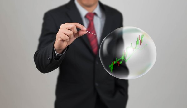 A man in a suit about to burst a bubble with a stock chart on it