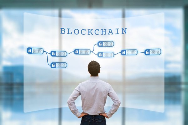 A person dressed in a buttondown shirt and jeans looking at a diagram of a blockchain.