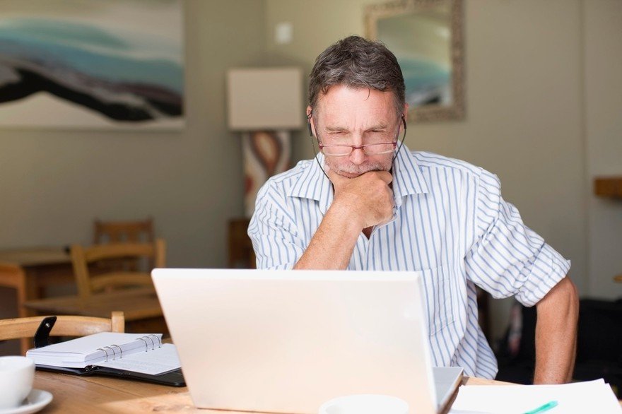 Older man staring intently at laptop screen.