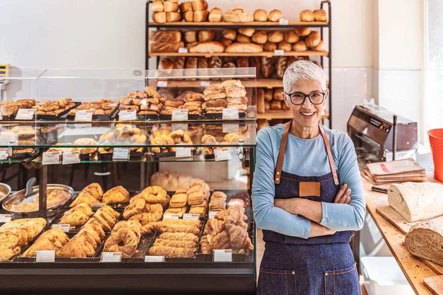Smiling person wearing an apron in a bakery. 