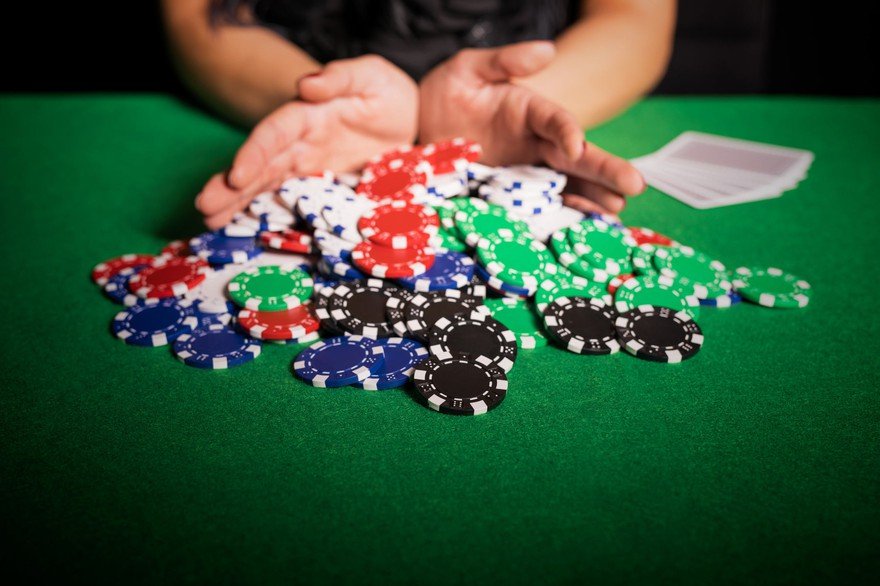 A gambler pushing their chips into the middle of the poker table.