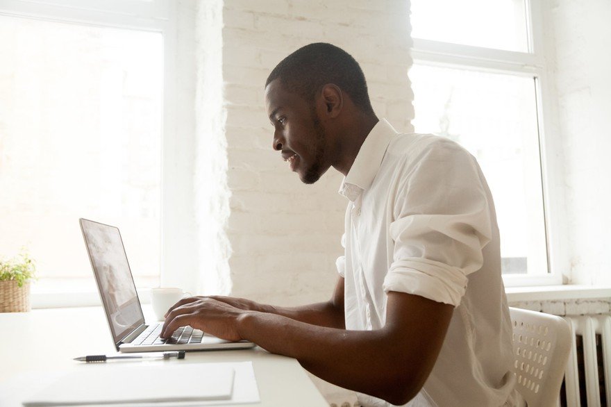 Businessman working on laptop sitting at home office desk.