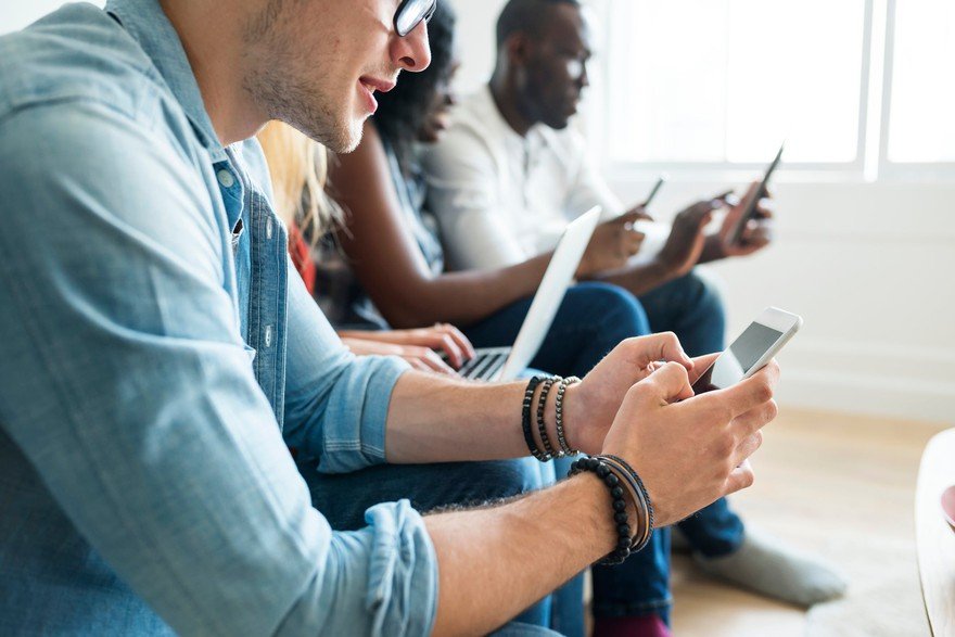 People seated using different technological devices.