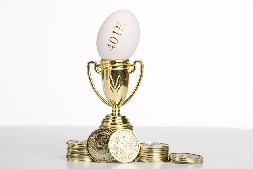 An egg marked "401K" in gold lettering sits inside a golden trophy, with gold coins scattered around the base.