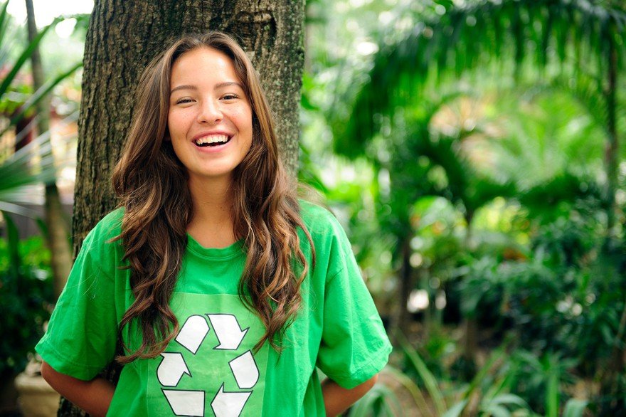 Young adult smiling, wearing a recycle t-shirt.