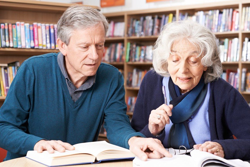 Mature couple reading books in a library.