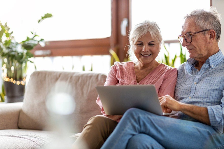 Adult couple smiling while looking at laptop at home.