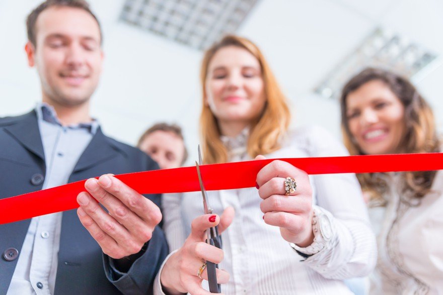 Office professionals standing together cutting a ribbon